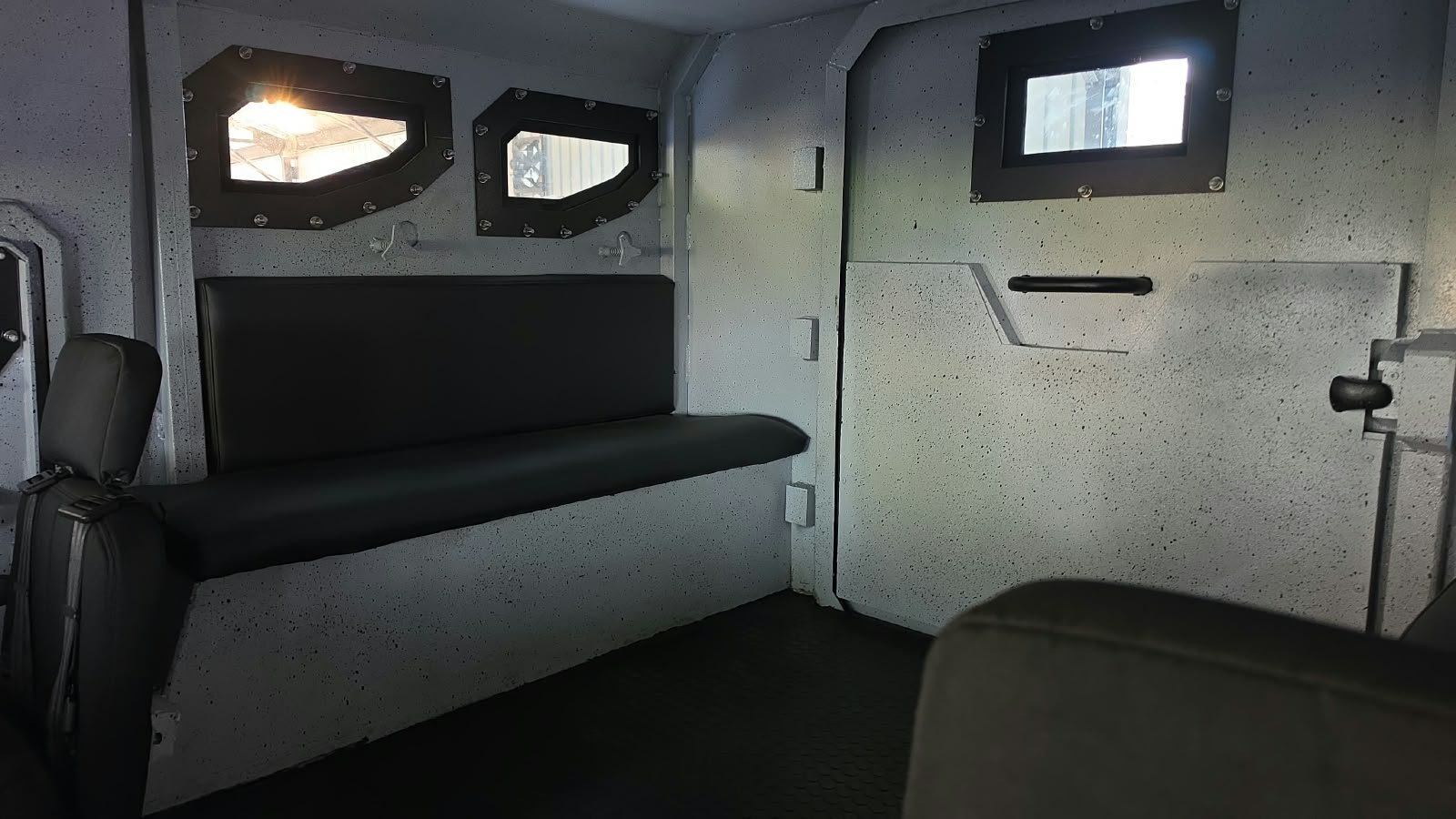 Interior de un habitáculo blindado con banca tapizada y ventanas blindadas de bordes reforzados